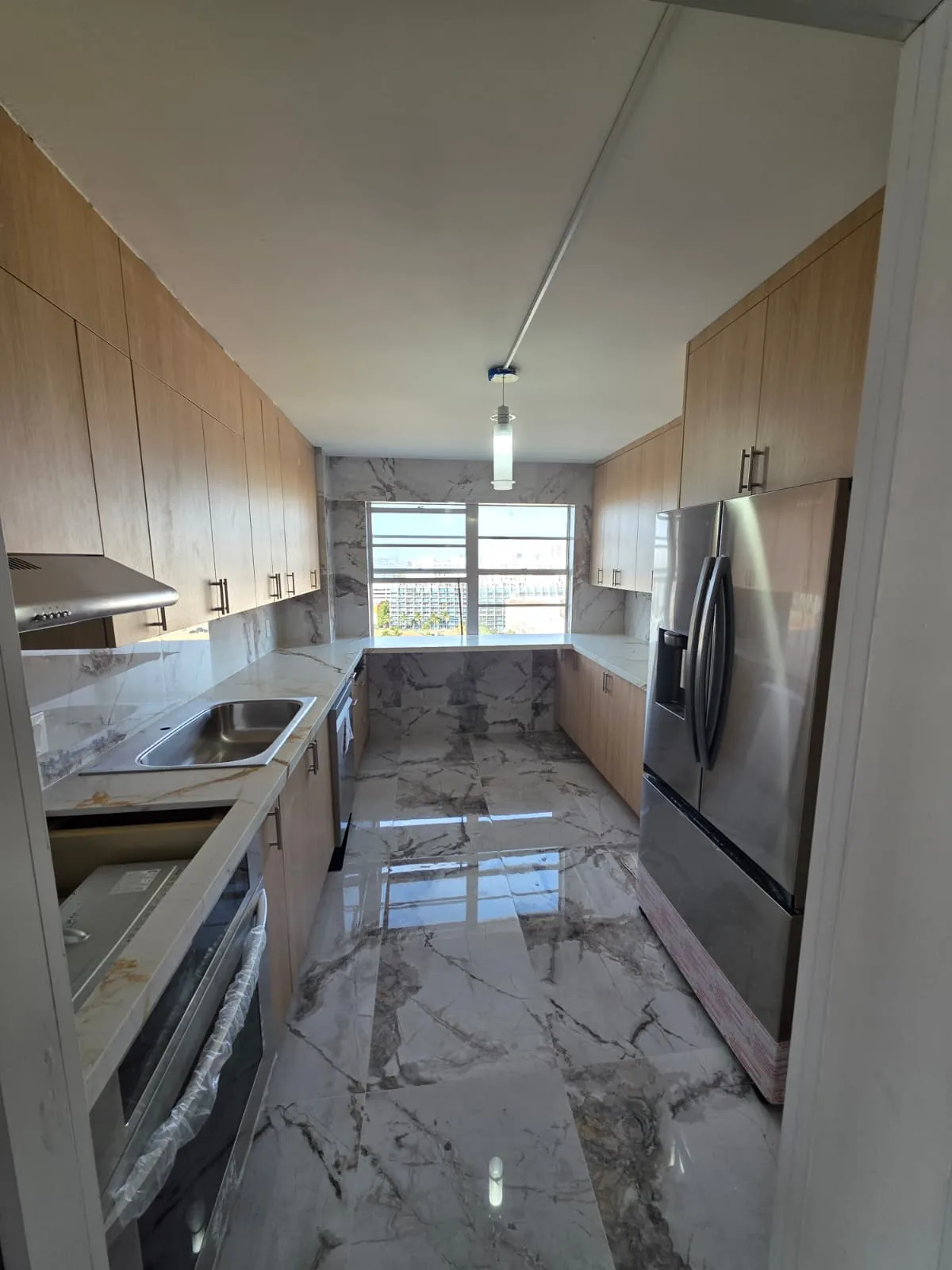 Galley kitchen in oak with marble floors and counters