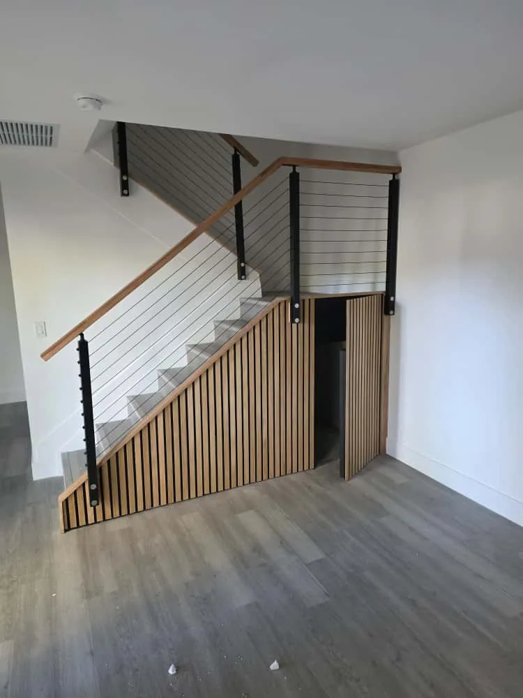 Staircase with wood slat wainscot and cable railing